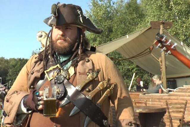 Ein als Pirat verkleideter Mann hält einen Krug Bier in der Hand.