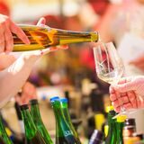 Eine Person schüttet einer anderen Person ein Glas Wein ein.