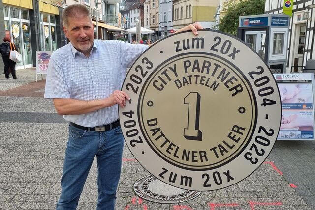 Ein Mann hält einen großen Plastiktaler hoch.
