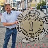Ein Mann hält einen großen Plastiktaler hoch.