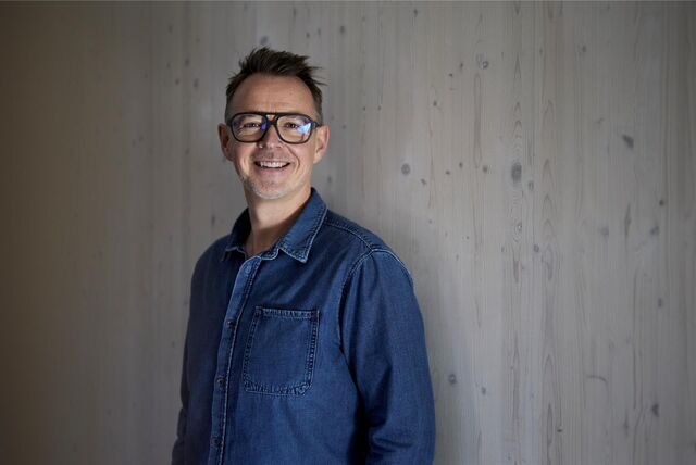 Holger Stromberg steht vor einer grauen Holzwand.