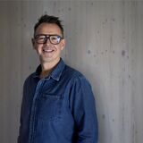 Holger Stromberg steht vor einer grauen Holzwand.