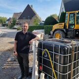 Ein Mann lehnt an einer Baustelle ab einer Absperrbake, im Hintergrund ein Bagger.