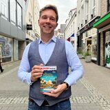 Jens Blome steht auf der Großen Geldstraße in Recklinghausen und hält sein Spiel „Das letzte Festmahl des Pharaos“ in den Händen.