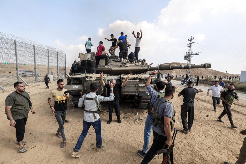 Palästinenser übernehmen die Kontrolle über einen israelischen Panzer, nachdem sie den Grenzzaun zu Israel in Khan Yunis überquert haben. Palästinenser übernehmen die Kontrolle über einen israelischen Panzer, nachdem sie den Grenzzaun zu Israel in Khan Yunis überquert haben.