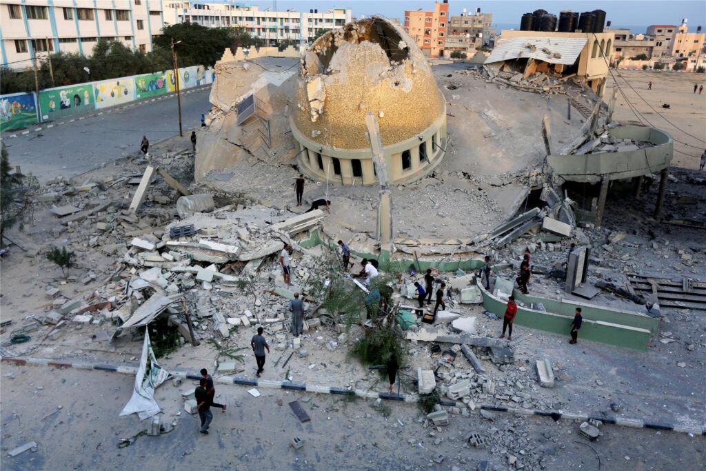 Menschen stehen vor einer Moschee, die bei einem israelischen Luftangriff in Khan Younis im Gazastreifen zerstört wurde. Menschen stehen vor einer Moschee, die bei einem israelischen Luftangriff in Khan Younis im Gazastreifen zerstört wurde.