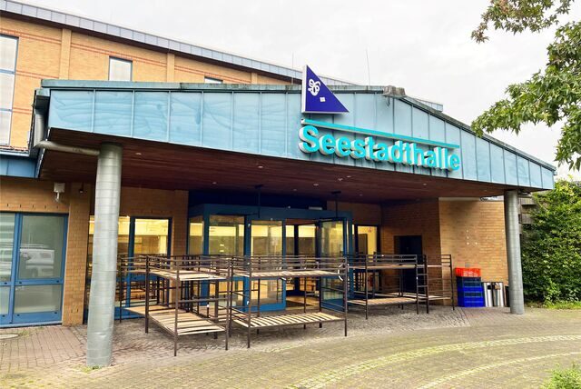 Die Seestadthalle von außen: Im Eingangsbereich stehen einige Bettgestelle.