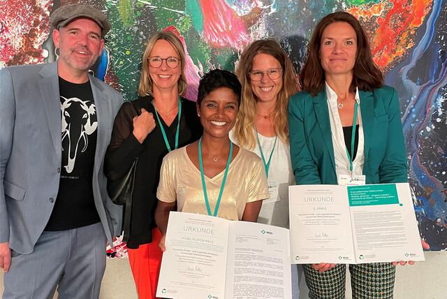 Ein Mann und vier Frauen zeigen Preise für das Kinderpalliativzentrum.