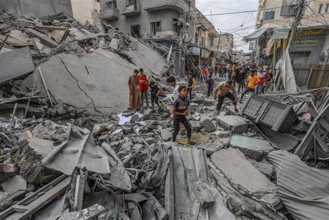 Palästinenser laufen nach einem israelischen Luftangriff im Gazastreifen zwischen den Trümmern eines zerstörten Gebäudes umher.