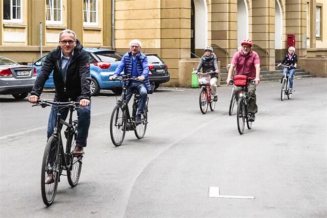 Mehrere Menschen fahren mit dem Fahrrad am Dattelner Rathaus vorbei.