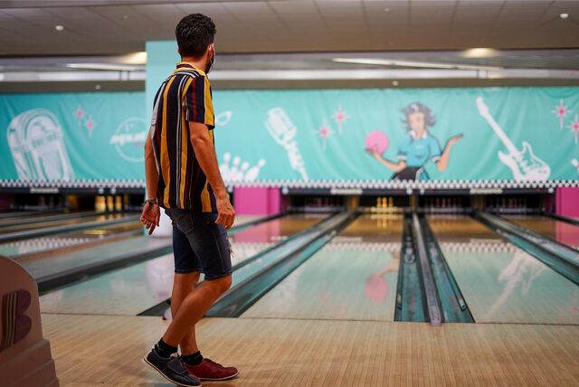 Ein Mann steht an einer Bowlingbahn.