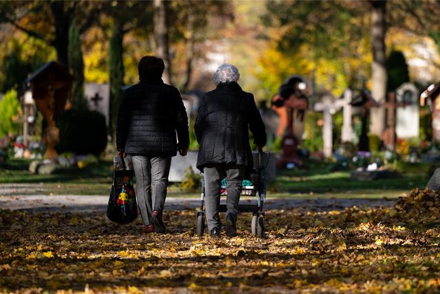 Zwei Frauen laufen an Allerheiligen, am 01. November, über den Friedhof.