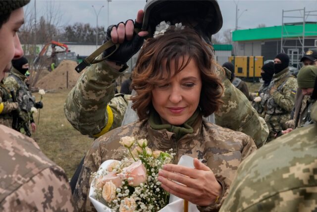 Ein Soldat hält einen Helm als Hochzeitskrone während der Hochzeitszeremonie für die Mitglieder der ukrainischen Territorialen Verteidigungskräfte Lesia Ivashchenko und Valerii Fylymonov, an einem Kontrollpunkt in Kiew.