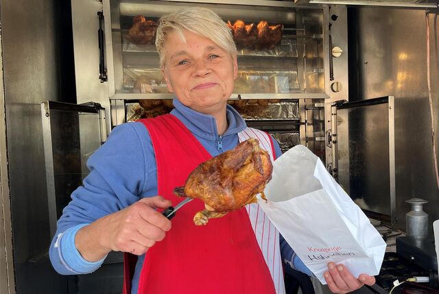 Imbissverkäuferin Martin Rüter packt ein gegrilltes Hähnchen in eine Tüte.