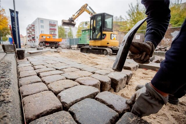 Ein Bauarbeiter setzt Pflastersteine. Bisher müssen Anlieger Straßenmodernisierungen oft mitfinanzieren.