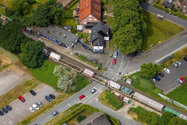 Der Sythener Bahnhofsbereich von oben, ein Güterzug fährt bei geschlossener Schranke durch den Ort.