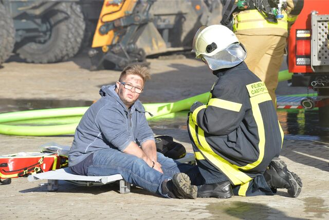 Die Feuerwehr rettet einen Mitarbeiter aus dem verrauchten Firmengebäude. Das Ganze ist allerdings nur eine Übung, der „Mitarbeiter“ ist als Brandopfer geschminkt.