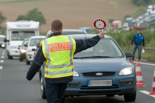 Ein Polizeibeamter winkt auf einer Autobahn einen Autofahrer heraus (Symbolbild).
