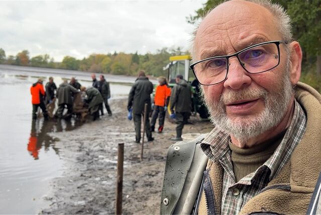 Fischzuchtmeister Dieter Schwarten steht am Dülmener See. Im Hintergrund halten einige Männer ein Fischnetz fest.