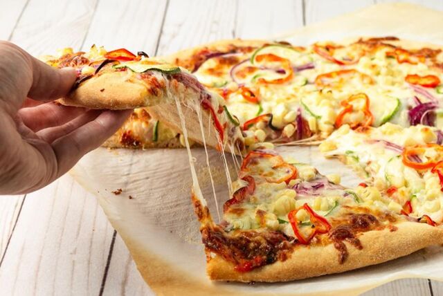 Eine Hand greift nach einem Stück Pizza.