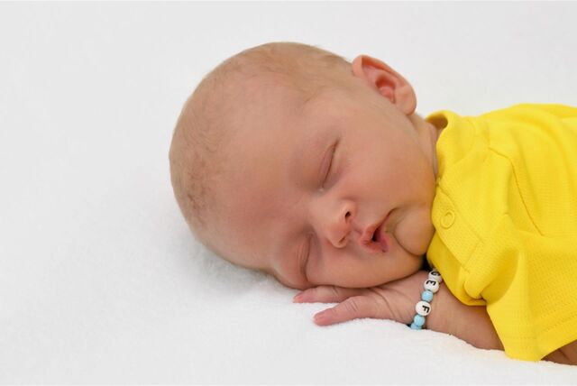 Ein Baby mit gelbem Oberteil ist schlafend zu sehen.