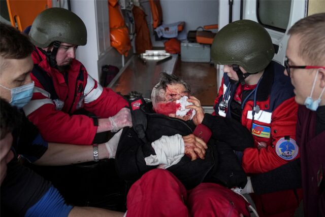 Sanitäter transportieren eine durch Granatenbeschuss verwundete Frau auf einer Trage in ein Entbindungskrankenhaus, das in eine Krankenstation umgewandelt wurde, in Mariupol, Ukraine.