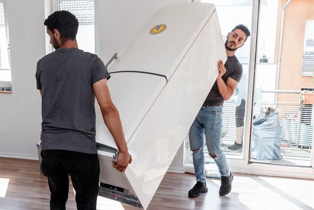 Zwei Männer tragen einen Kühlschrank