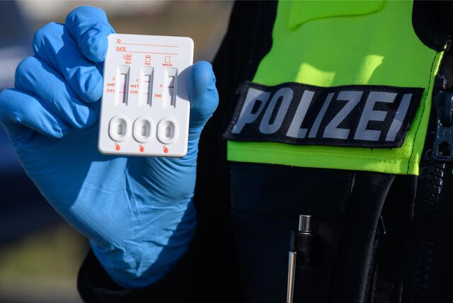 Ein Polizist hält einen Drogentest hoch.