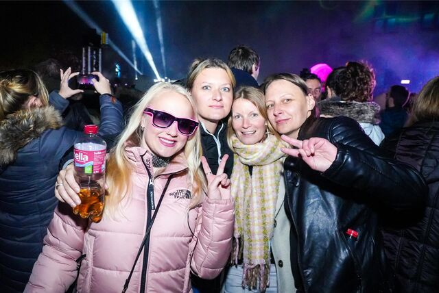 Vier junge Frauen stehen zusammen und lächeln in die Kamera.