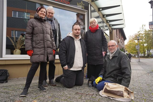 Menschen knien vor Stolpersteinen