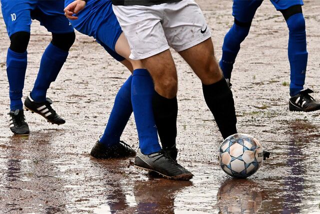 Vier Fußballspieler auf einem Ascheplatz.