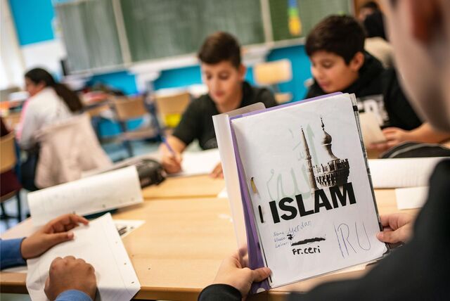 Der Schüler Merdan öffnet seinen seinen selbst gestalteten Ordner beim Islamunterricht in einer siebten Klasse.