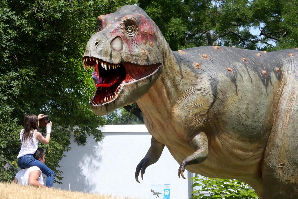 Zwei Personen stehen am Planetarium Bochum vor einer Tyrannosaurus Rex Figur