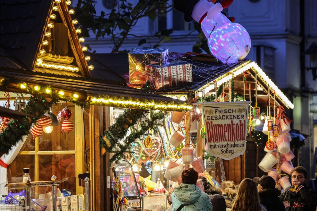 Auf dem Weihnachtsmarkt in Essen-Steele kaufen Personen Süßigkeiten an den Buden