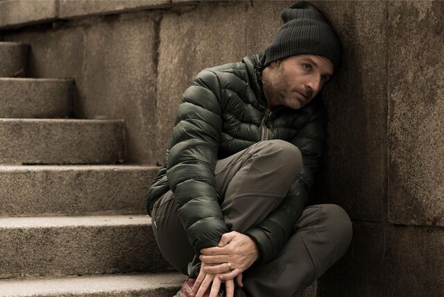 mann sitzt in winterkleidung depressiv auf einer treppe