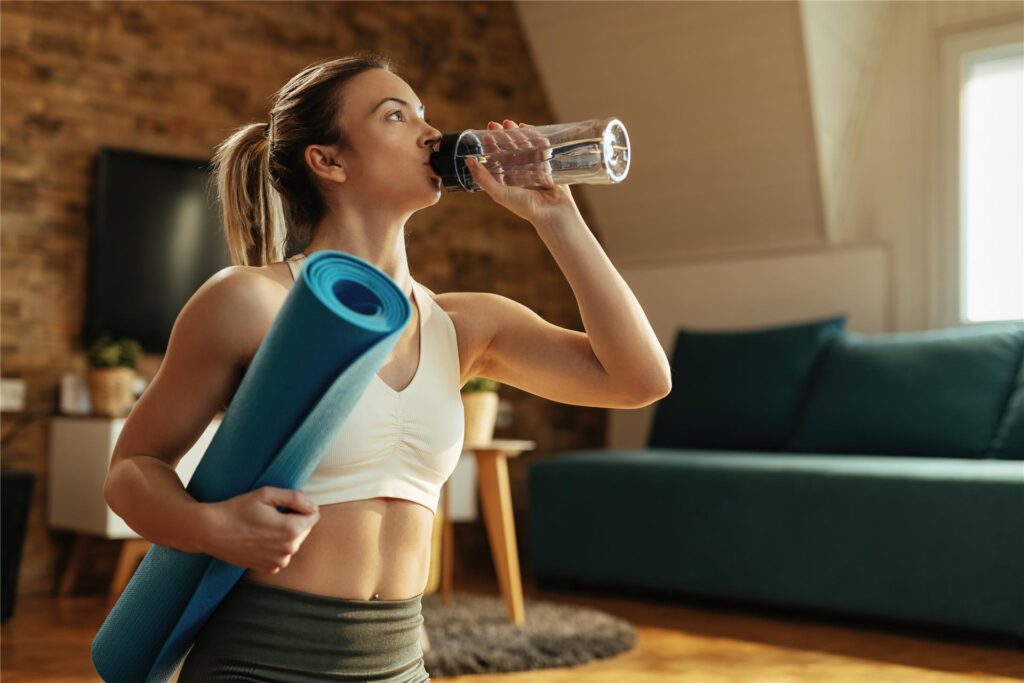 frau macht sport zu hause und trinkt wasser frau macht sport zu hause und trinkt wasser