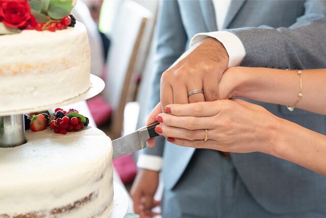Ein Brautpaar schneidet die Hochzeitstorte an.