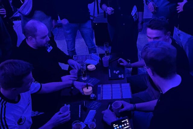 Vier Männer sitzen an einem Tisch und spielen das Würfelspiel Schocken.