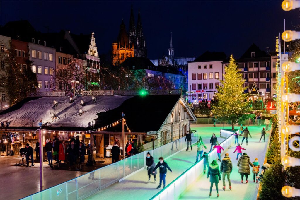 Personen fahren Schlittschuh auf der Eisbahn auf dem Weihnachtsmarkt Heumarkt
