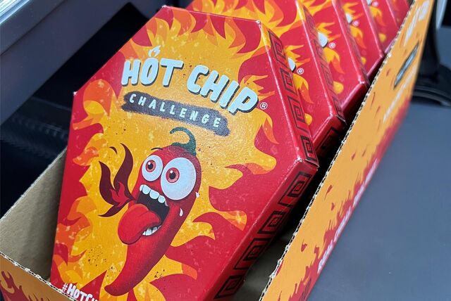Mehrerer Packungen der „Hot Chip Challenge“ liegen in einem Pappkarton.