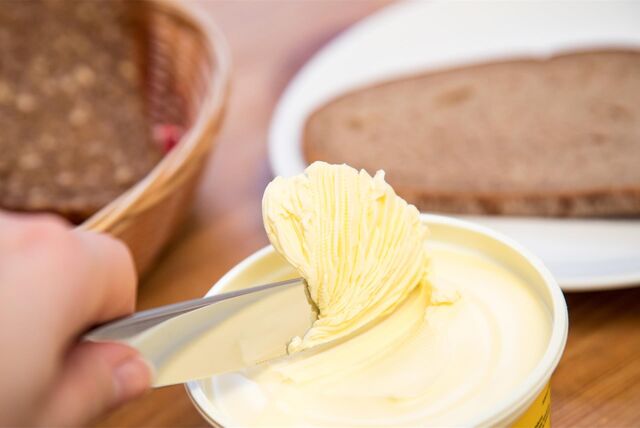 Eine Person holt mit einem Messer Margarine aus einer Packung.
