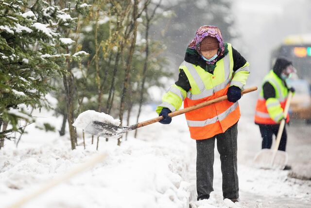 Zwei Frauen befreien eine Straße von Schnee.