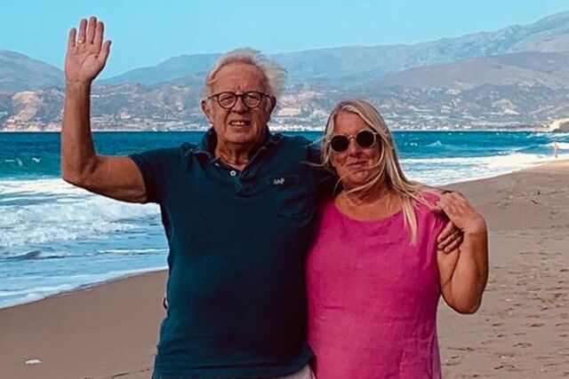 Achim Lorenz und Andrea Hennecke stehen auf Kreta am Strand und winken.