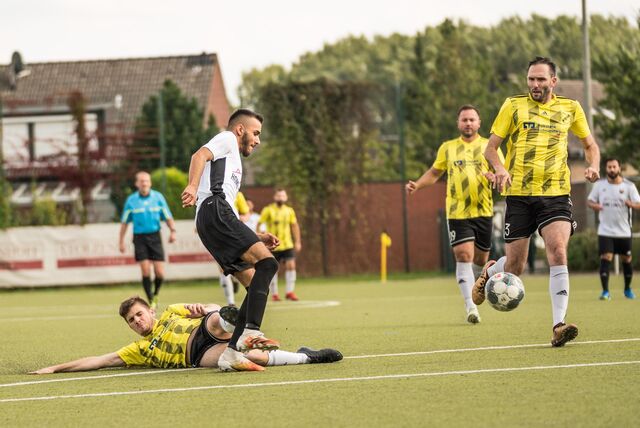 Timo Tetzlacht (r.) schaut auf dem Ball. Neben ihm ein grätschender Mitspieler und stehender Gegenspieler.
