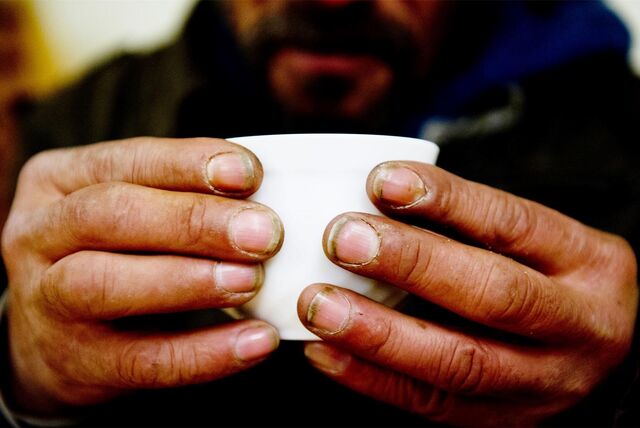 Zwei schmutzige und ungepflegte Männerhände umgreifen eine weiße Tasse. (Symbolbild)