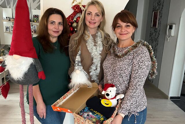 Drei Frauen zeigen einen Karton mit Spenden für die Ukraine.