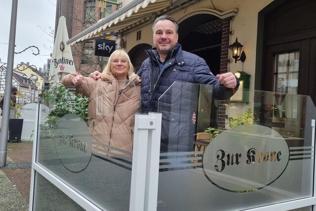 Eine Frau und ein Mann stehen vor einer Kneipe.