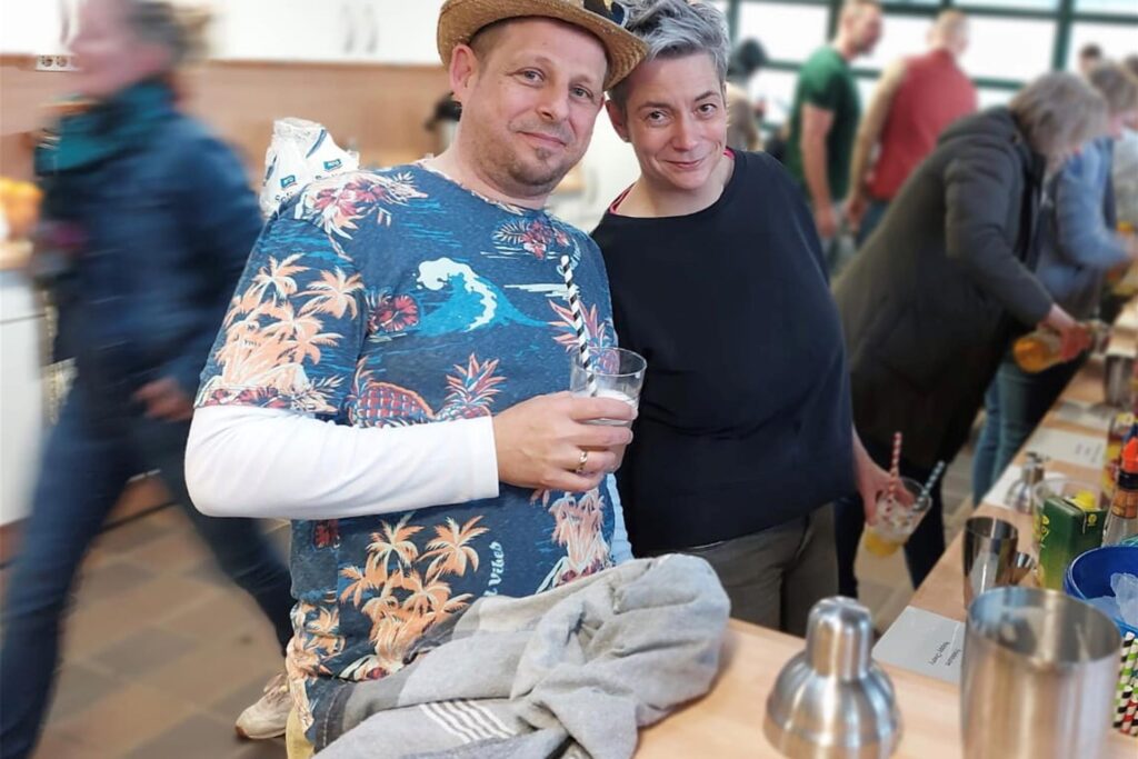 Mann mit buntem T-Shirt und Frau an einer Cocktailstation
