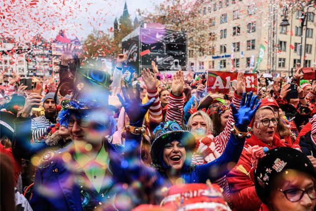 Lachende Menschen sind bunt verkleidet und laufen beim  Kölner Karnevalsumzug mit