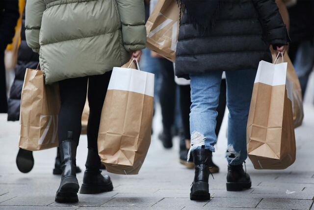 Frauen tragen am verkaufsoffenen Sonntag Einkaufstüten durch die Fußgängerzone.